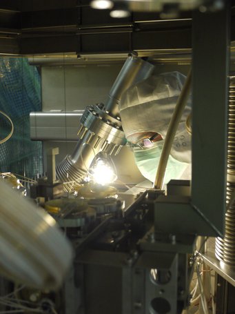 Erhellende Forschung: Für den Detektor GEO600 haben die Wissenschaftler innovative Technologien entwickelt, die weltweit auch in anderen Anlagen dieser Bauart eingesetzt werden. Eine Person in Schutzkleidung und Maske arbeitet konzentriert an einer technischen Apparatur in einem Laborumfeld.