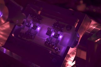 Close-up of an optical device illuminated by purple light.