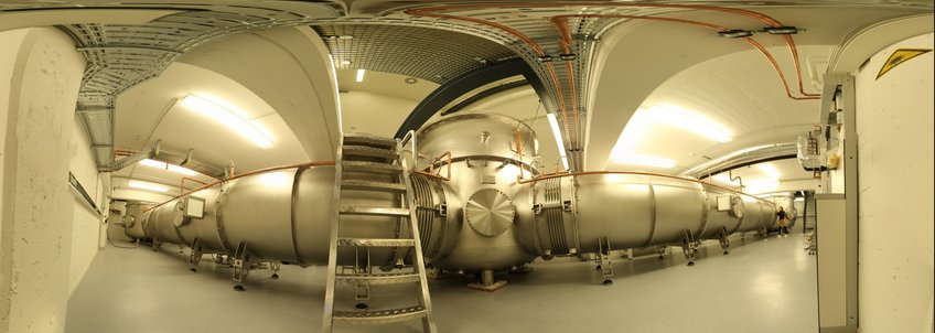 Panorama shot of the 10 meter prototype at the Max Planck Institute for Gravitational Physics in Hannover. It is used for demonstrations and tests of technologies for the third generation of gravitational-wave detectors. Panoramic photograph of a large metallic cylindrical structure in a laboratory setting.