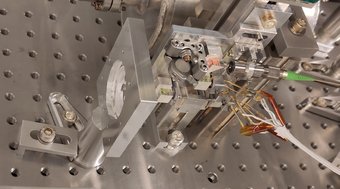Fits in the palm of your hand and weighs about as much as a grapefruit: The newly developed inertial sensor (on the left in the circular hole in the metal frame) and the highly sensitive laser sensing system. (on the right) Complex assembly of optical components and wires on the metal surface of an optical table.