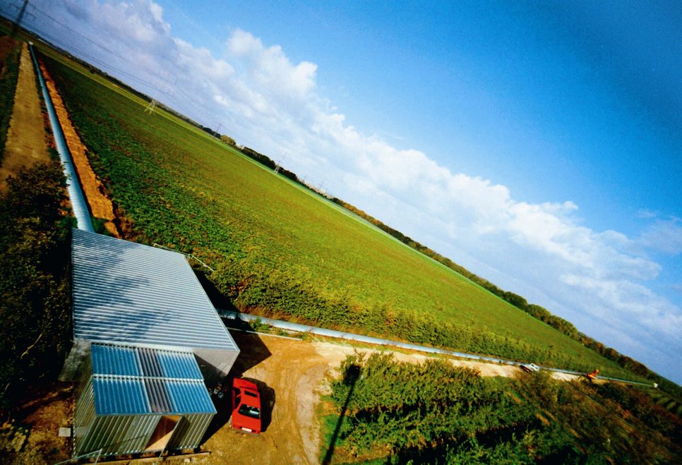 Test for new technologies: In Ruthe near Hanover, GEO600 stretches out its two 600-metre arms. At its heart is the building in the centre housing the laser system (rear left).
 