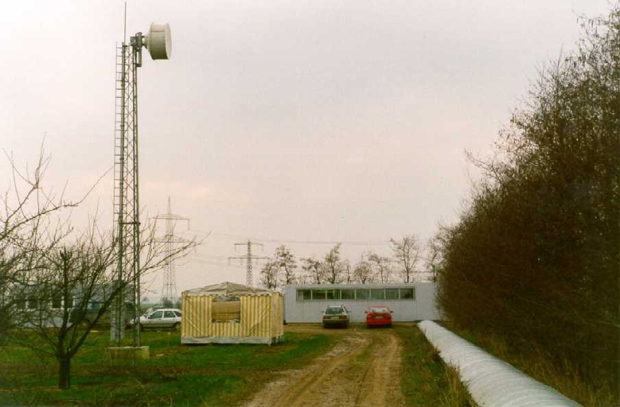 The tent at the feet of the transmitter mast serves as stores. In the back one can see at left the workshop container. The automobiles surrounding the central building indicate the activities at the site.