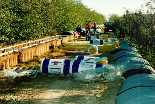 The trench has been uncovered; the curved pieces of corrugated iron lie on the right-hand side. The bales of rockwool have been distributed along the trench.